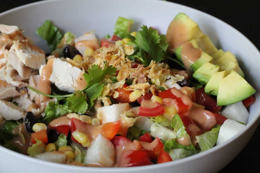 A large bowl with a chopped salad, avocado, and chicken.