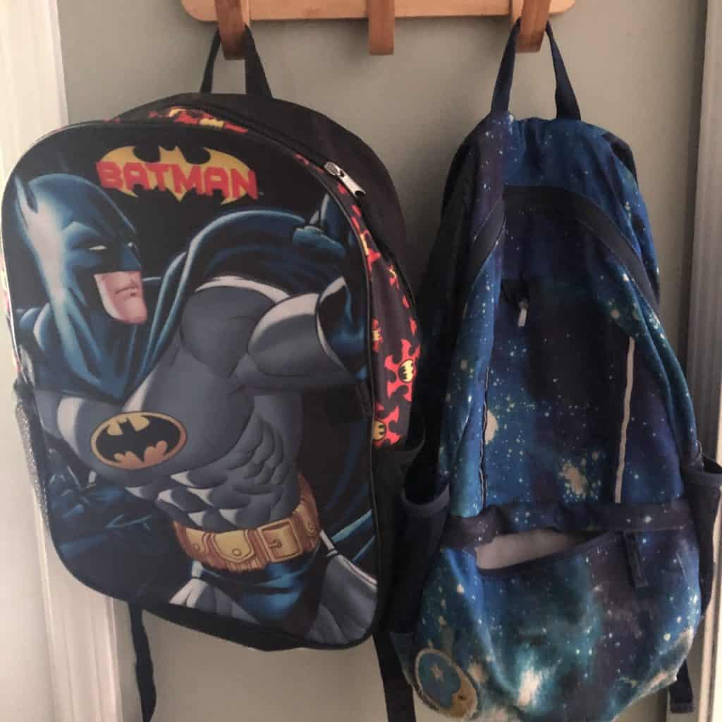 Two backpacks hang on wall hooks.