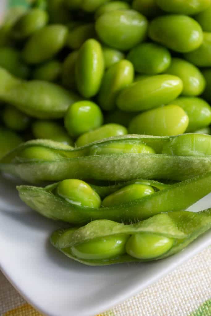 A close-up shot of three edamame pods with beans peeking out.