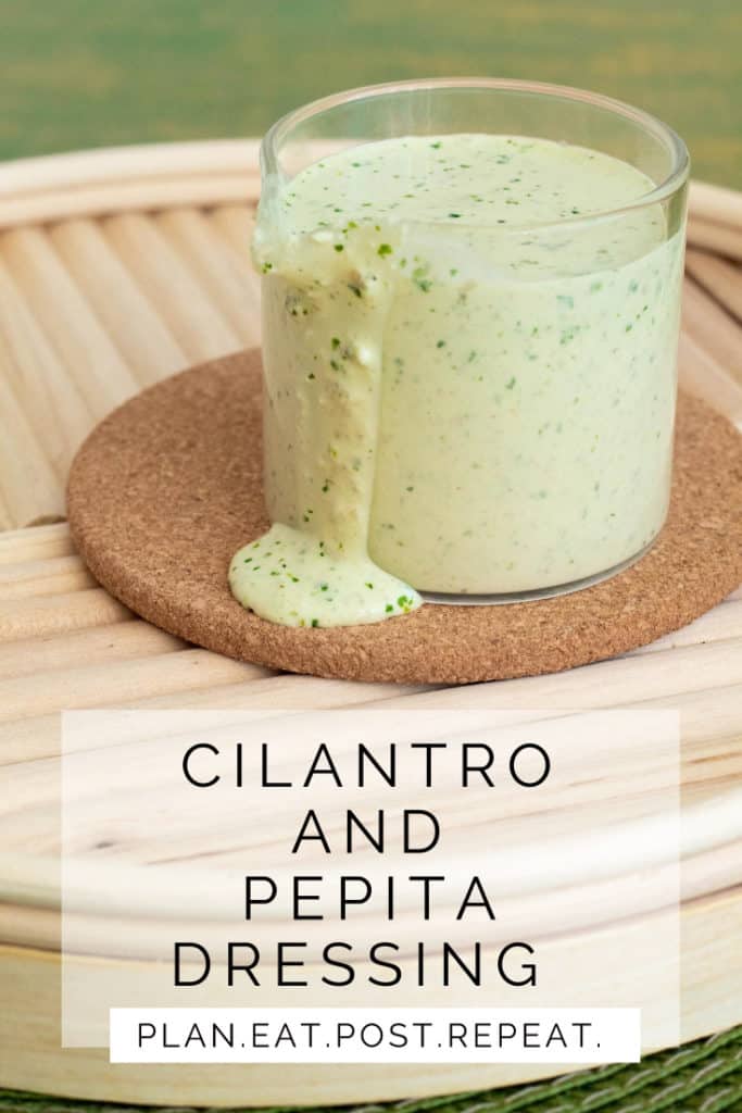 A glass jar of pale green sauce drips on to a cork surface.  The words, "Cilantro and Pepita Dressing" are in a white box at the bottom.