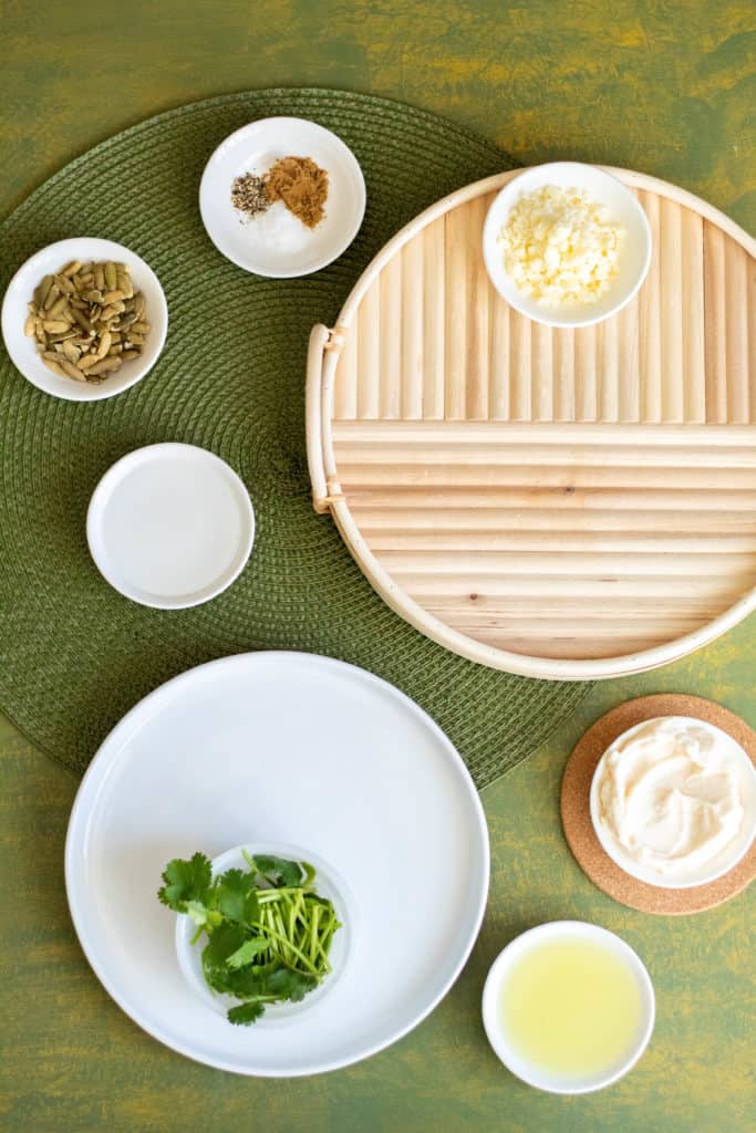 An arrangement of several bowls of ingredients over a green background.