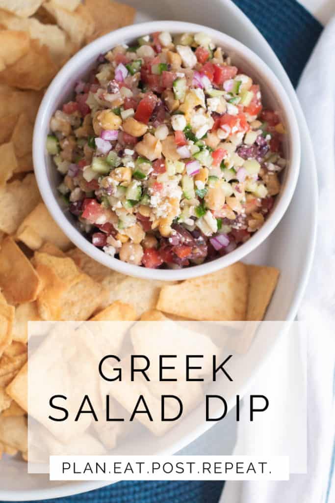 A bowl of Greek Salad Dip sits in a platter of pita chips.