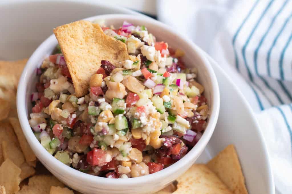 A close up photo of the texture of Greek Salad Dip in a white bowl.