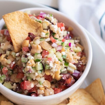 A close up photo of the texture of Greek Salad Dip in a white bowl.