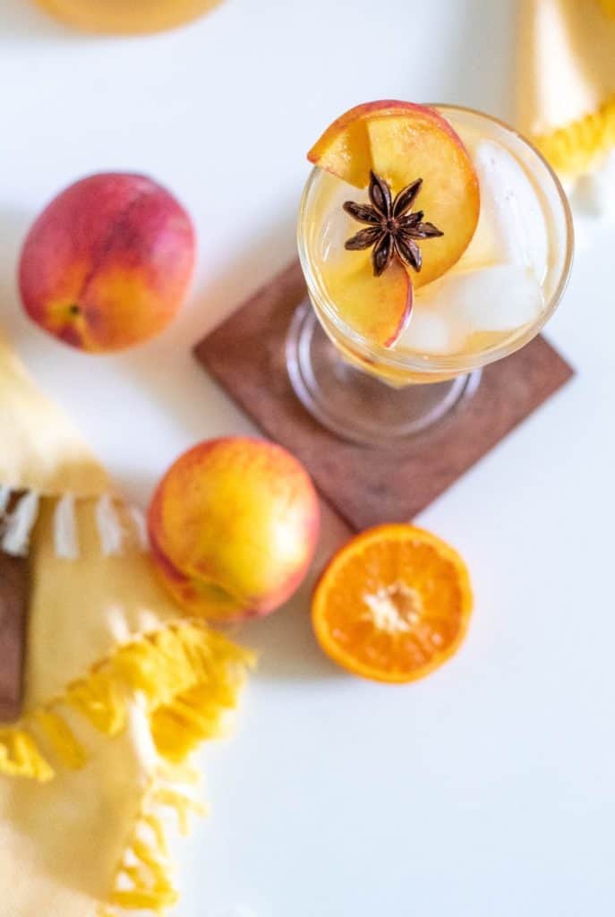 An overhead shot of a glass of sangria with a star anise and slices of nectarine.