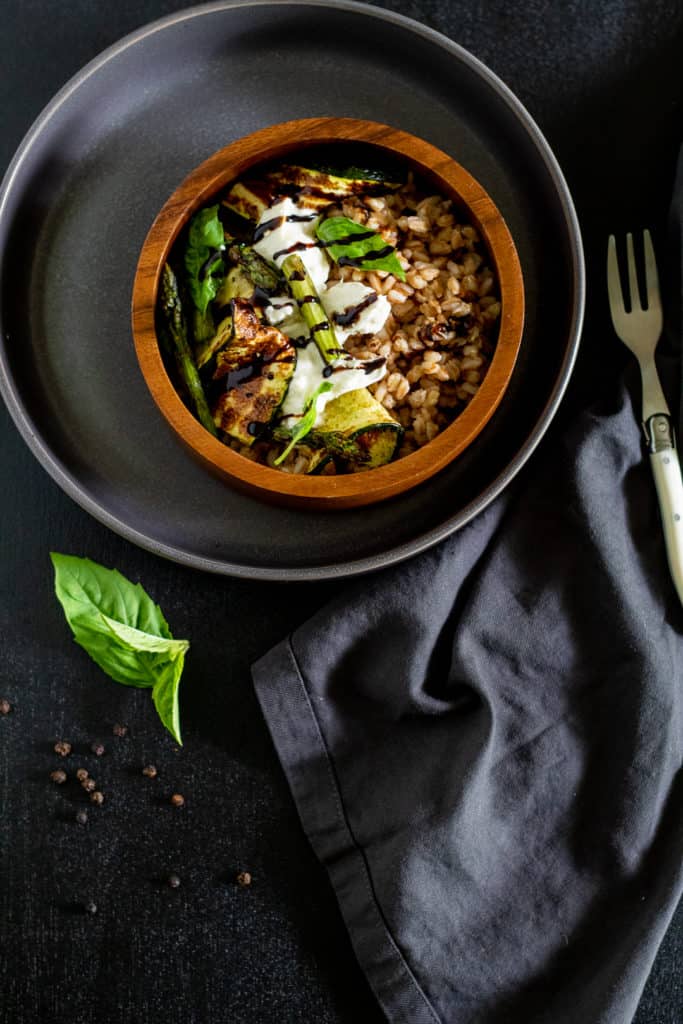 Grilled Zucchini and Burrata Bowl over a gray surface with basil leaves and a white fork nearby.