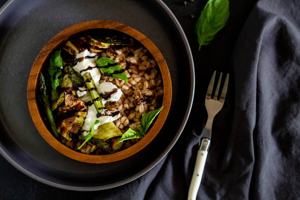 Grilled Zucchini and Burrata Bowl over a gray surface with basil leaves and a white fork nearby.