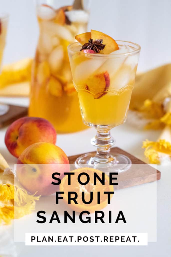 A glass of stone fruit sangria on a wooden coaster with the words "stone fruit sangria" and plan. eat. post. repeat overlayed.