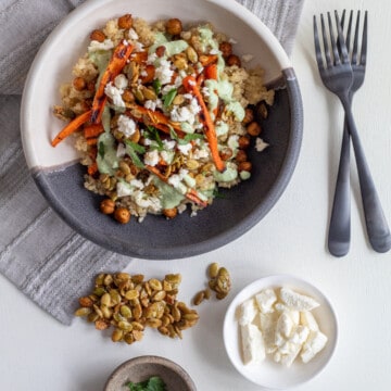 Extra toppings for the grain bowls sit alongside a serving on a white surface.