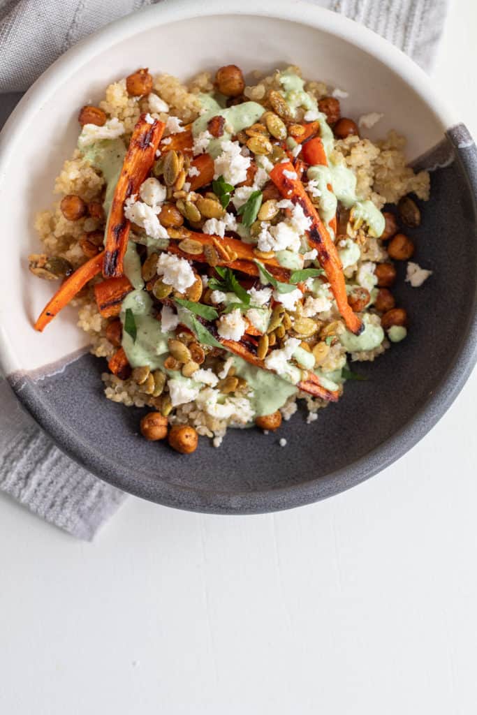 A serving of Roasted Carrot and Chickpea Grain Bowls sits on a white surface.