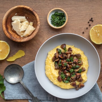 Polenta with Mushrooms and Gremolata rests on a gray napkin over a wooden surface.