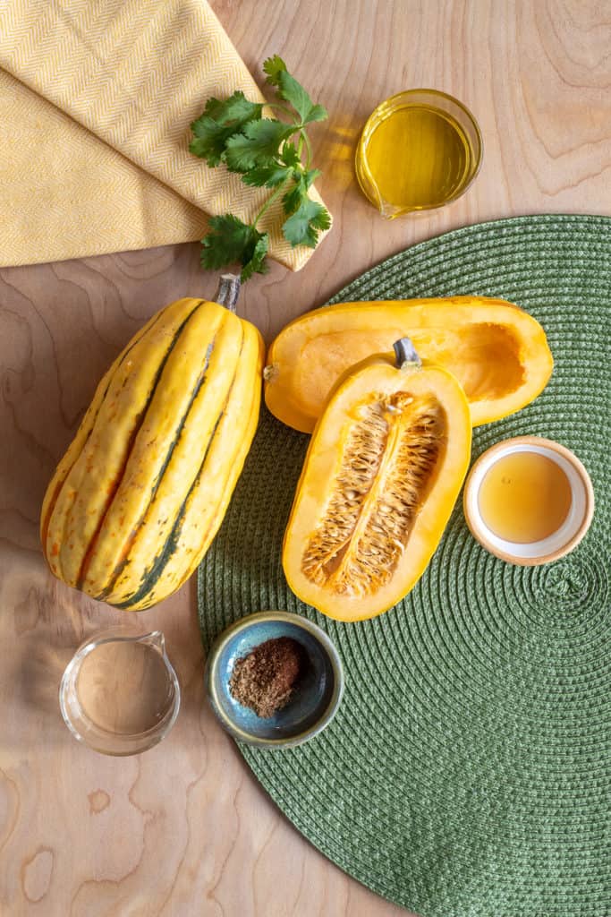 Ingredients for Roasted Delicata with Honey Ancho Vinaigrette are arranged over a light wooden surface.