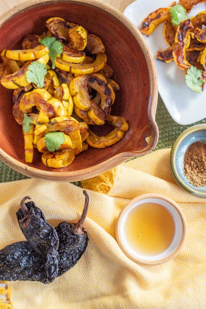 A serving of Roasted Delicata with Honey Ancho Vinaigrette sits on a green surface with a yellow napkin in the foreground.