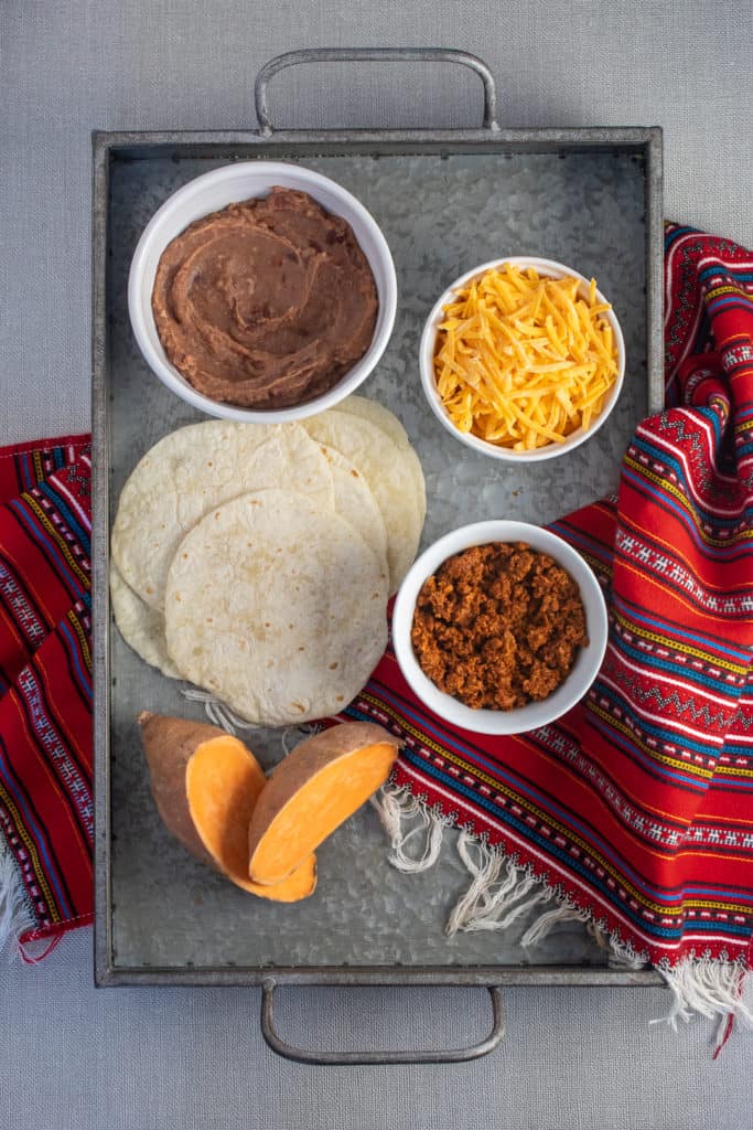 Ingredients for Baked Sweet Potato and Soyrizo Tacos are arranged on a silver tray.