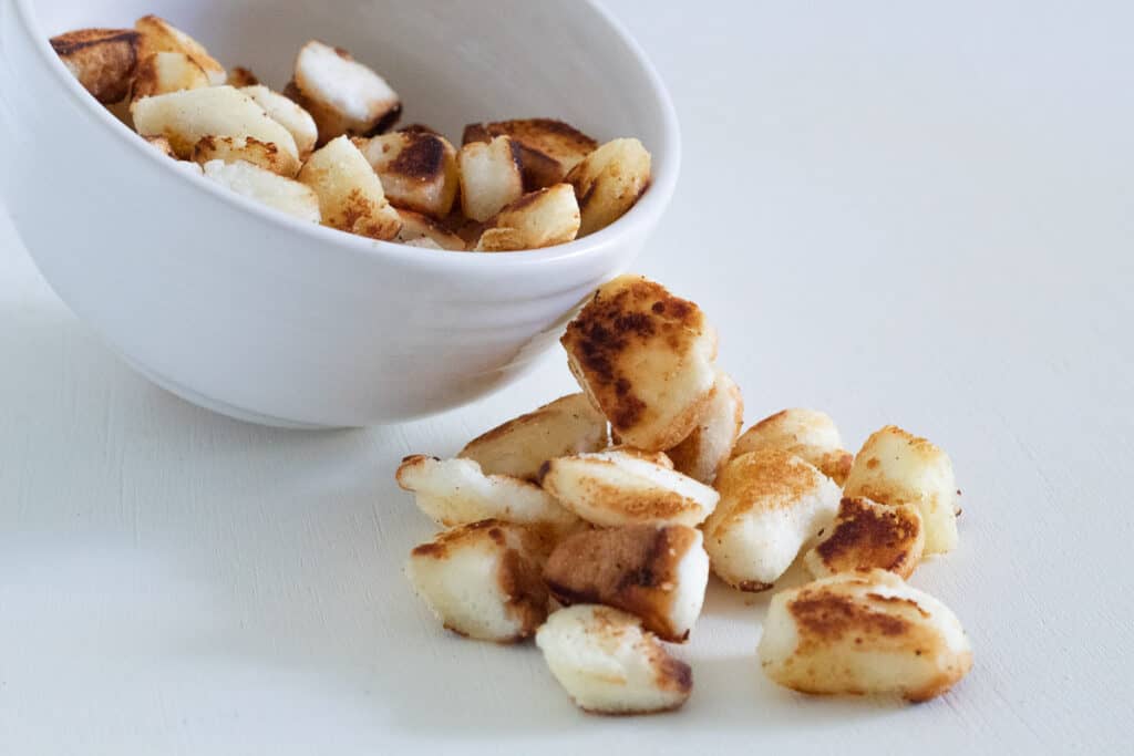 Golden toasted angel food cake croutons on a white surface.