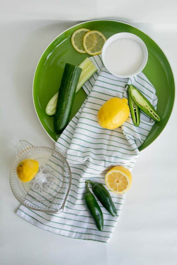 Ingredients for Fresh Cucumber Jalapeno Lemonade arranged over a round green platter.