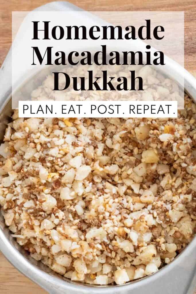 A brown mixture of spices, seeds, and nuts in a silver bowl with the words, "Homemade Macadamia Dukkah" and "Plan. Eat. Post. Repeat." superimposed over the top.