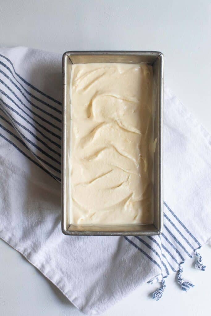 Pale yellow ice cream in a loaf pan ready for freezing.
