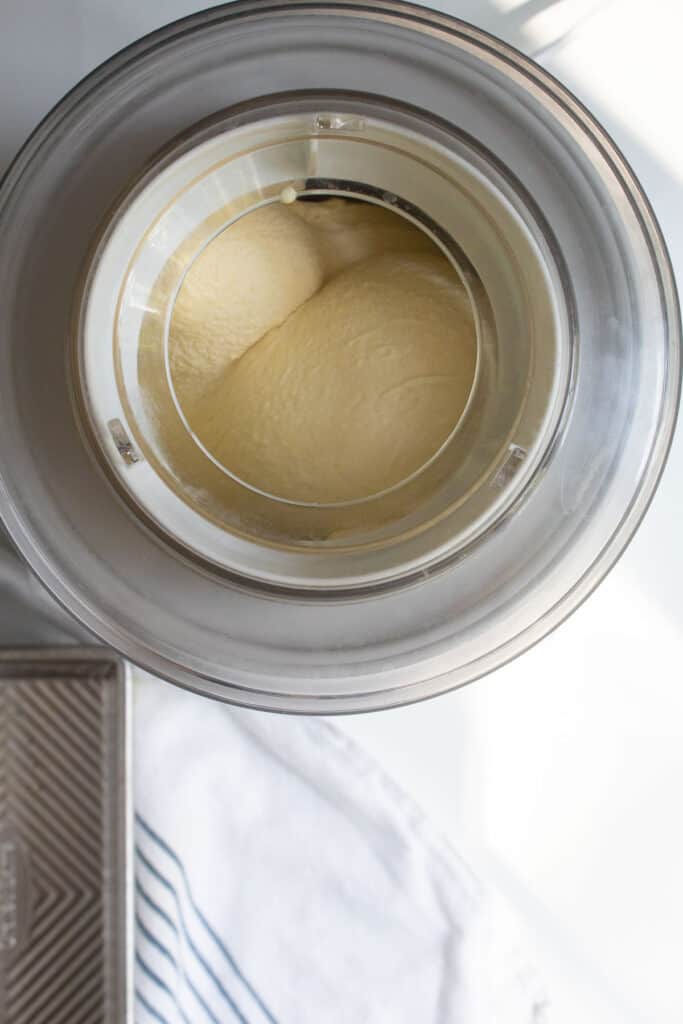 A top view of the ice cream maker churning the pale yellow ice cream mixture.