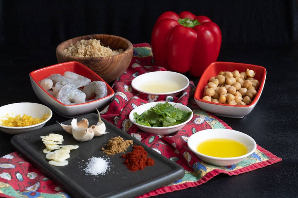 Ingredients for Garlic Paprika Shrimp Bowls with Chickpeas and Lemon displayed on a black background.