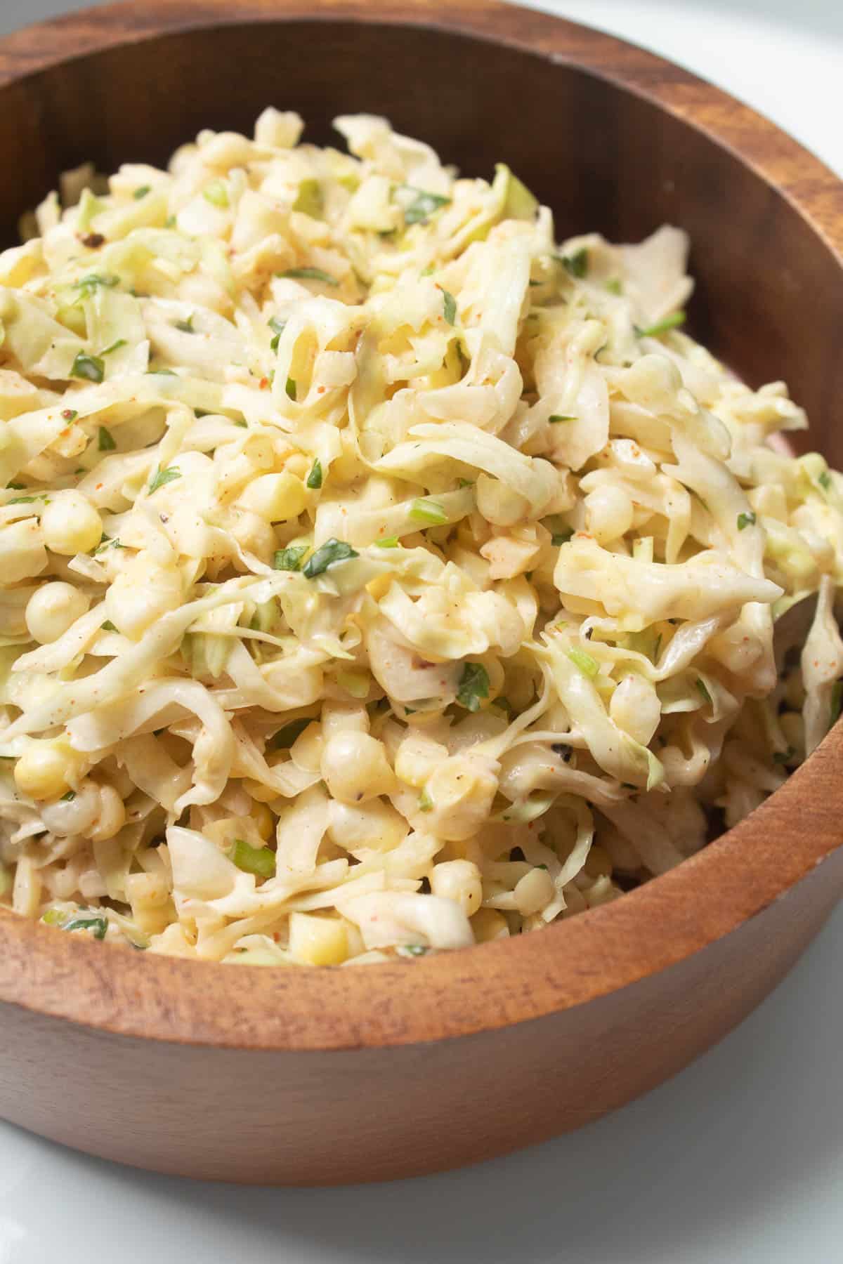 A pale yellow cabbage slaw with corn kernels and green flecks of cilantro.