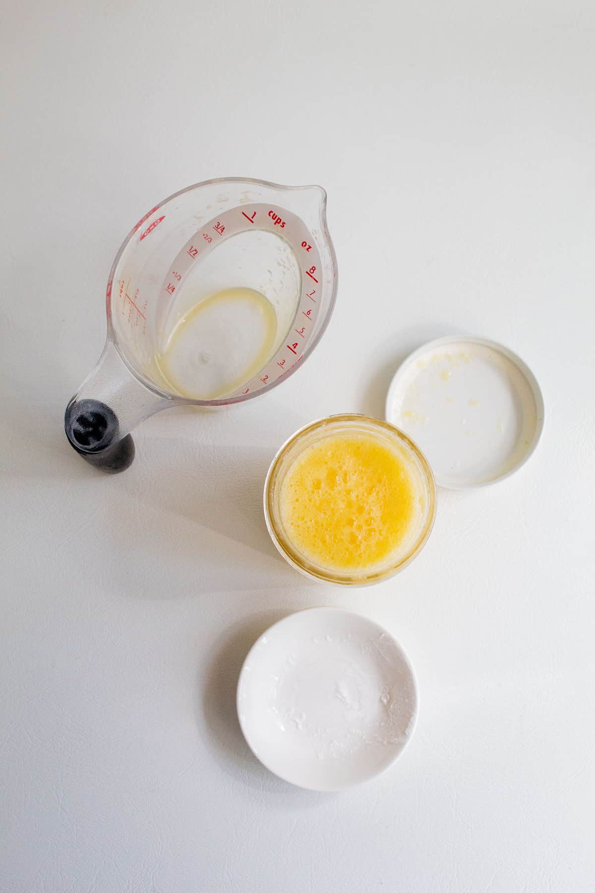 A measuring cup, jelly jar, and dish for the preparation of the orange juice and cornstarch slurry.