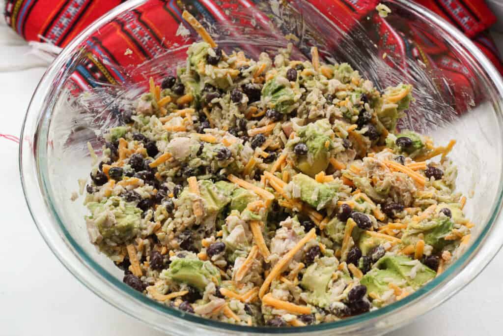 The burrito filling in a glass bowl with visible specks of cheese, black beans, avocado, and chicken.