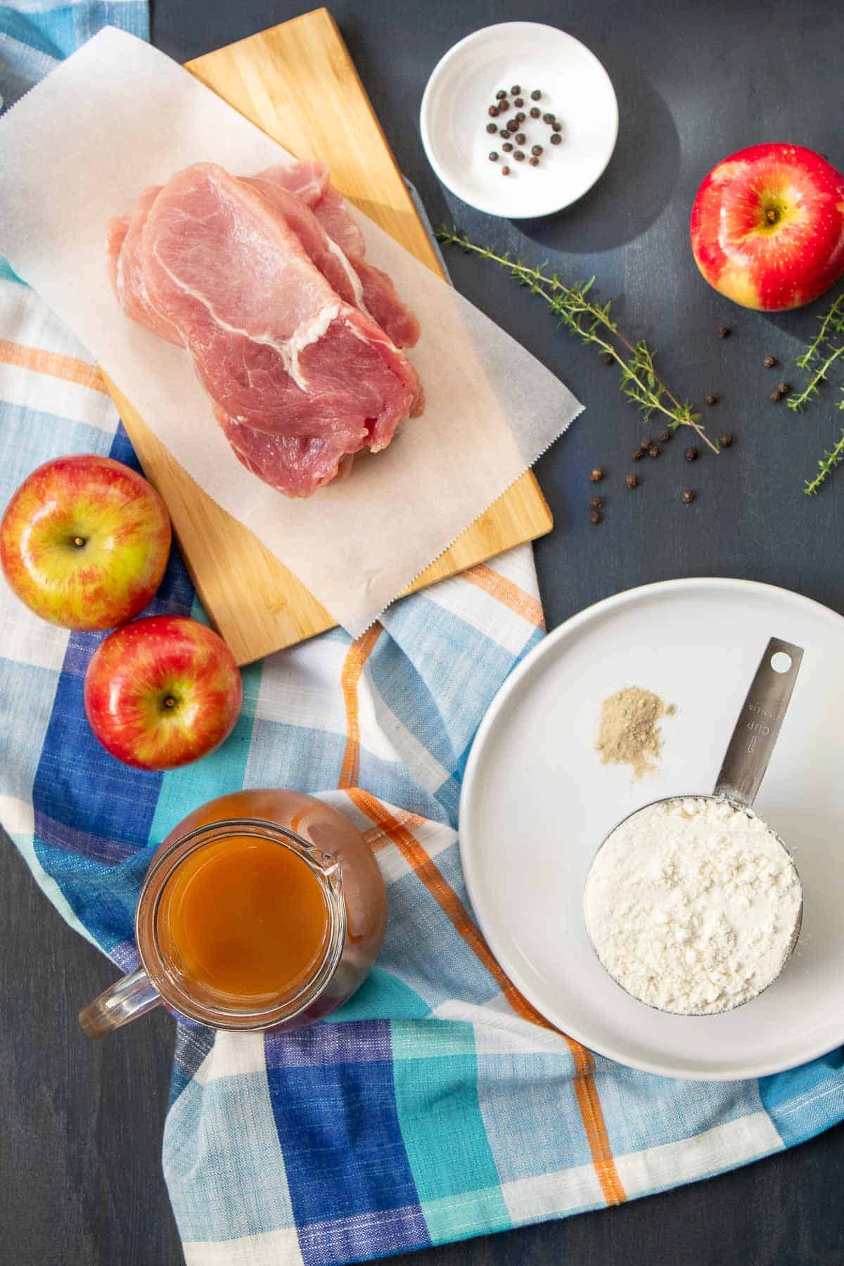 Ingredients for Crispy Breaded Pork Cutlets with Apple Cider Gravy are arranged on a dark surface.