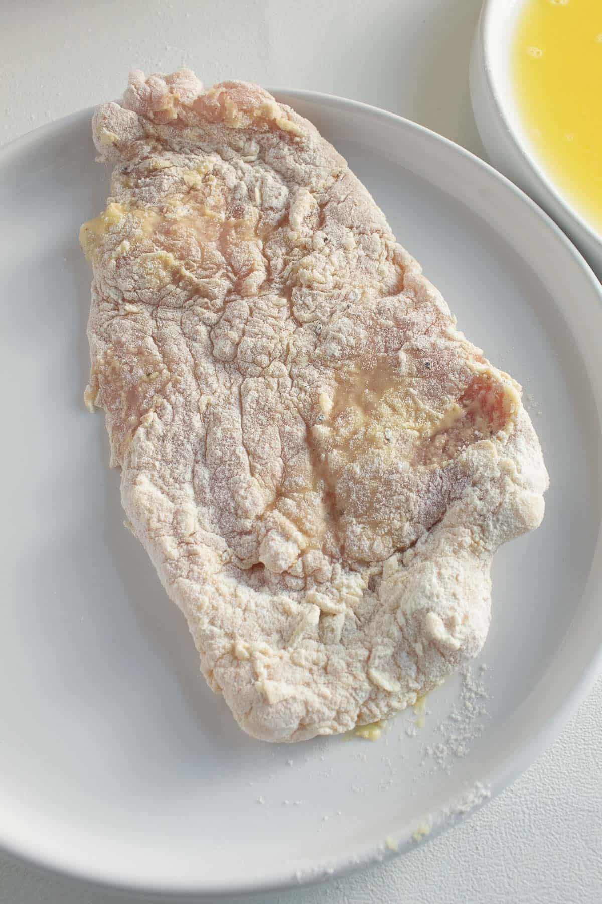 A detail view of a breaded pork cutlet on a white plate.