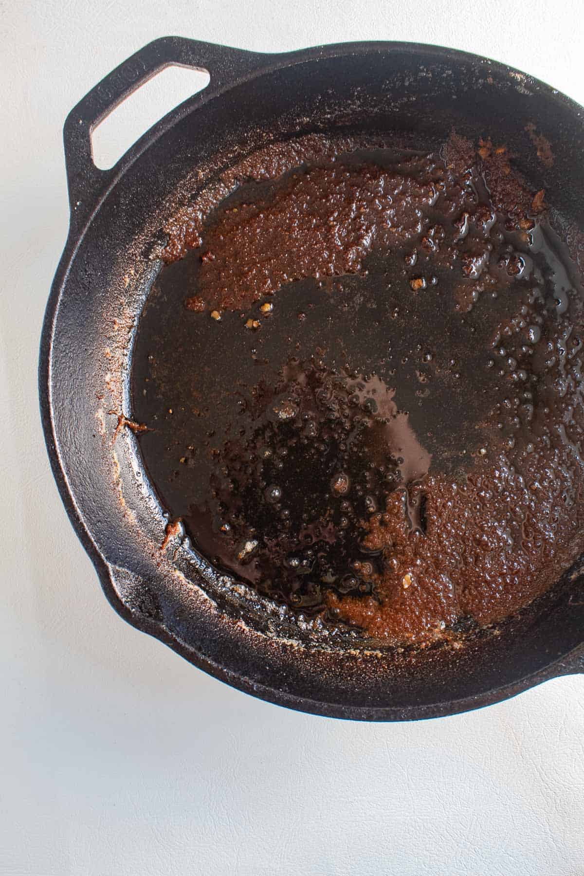 Browned flour and oil in the bottom of a cast iron skillet.