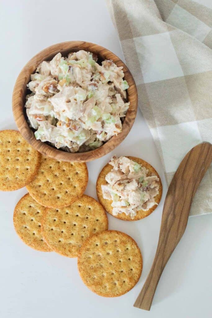 Chicken salad in a wooden bowl and spread on wheat crackers.