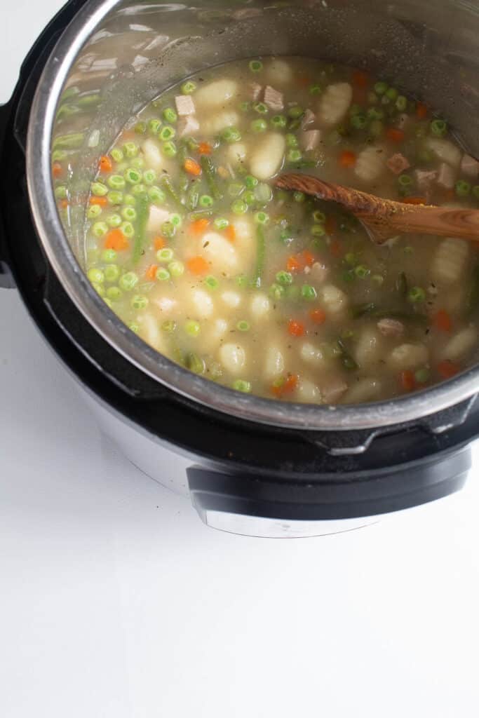 The soup once the pressure has been released from the Instant Pot, with peas, carrots, and green beans visible.
