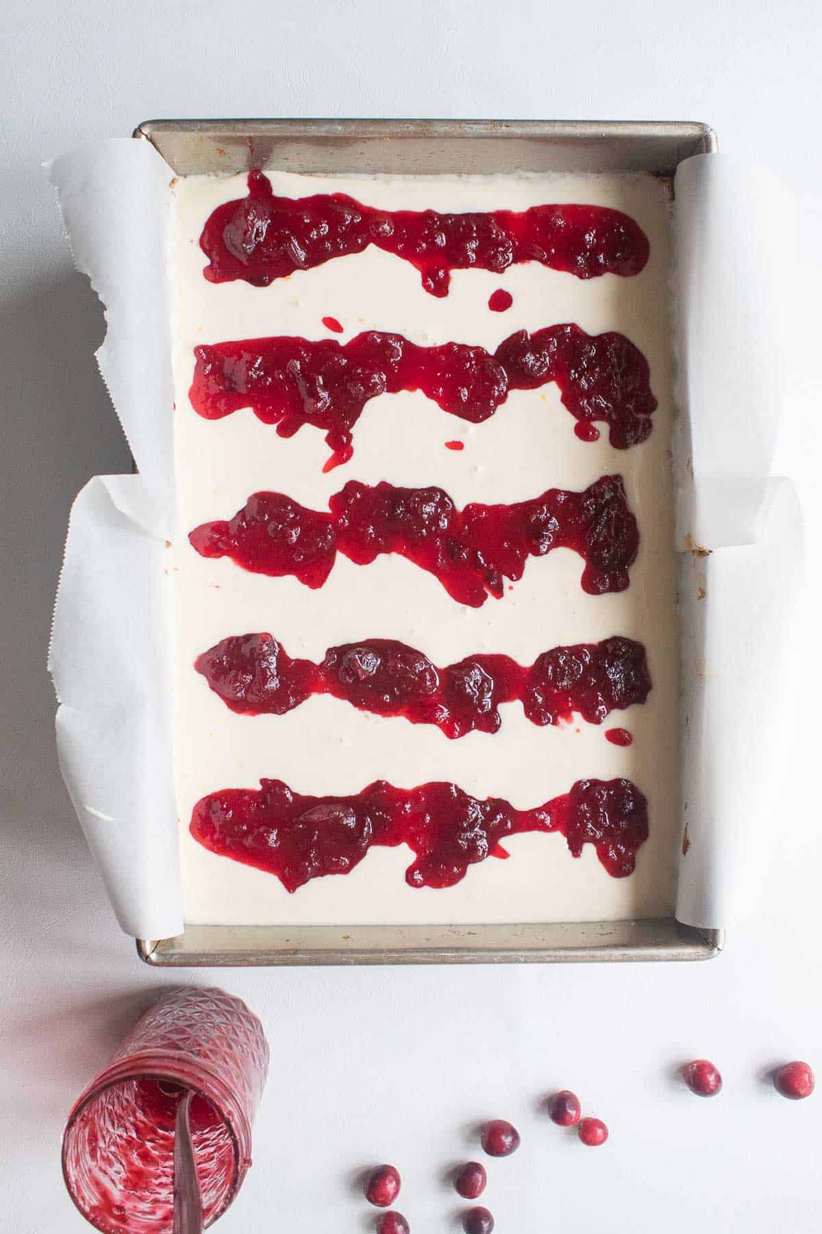 Rows of oramge cranberry jam spooned over the cheesecake filling to swirl for a marbled effect.