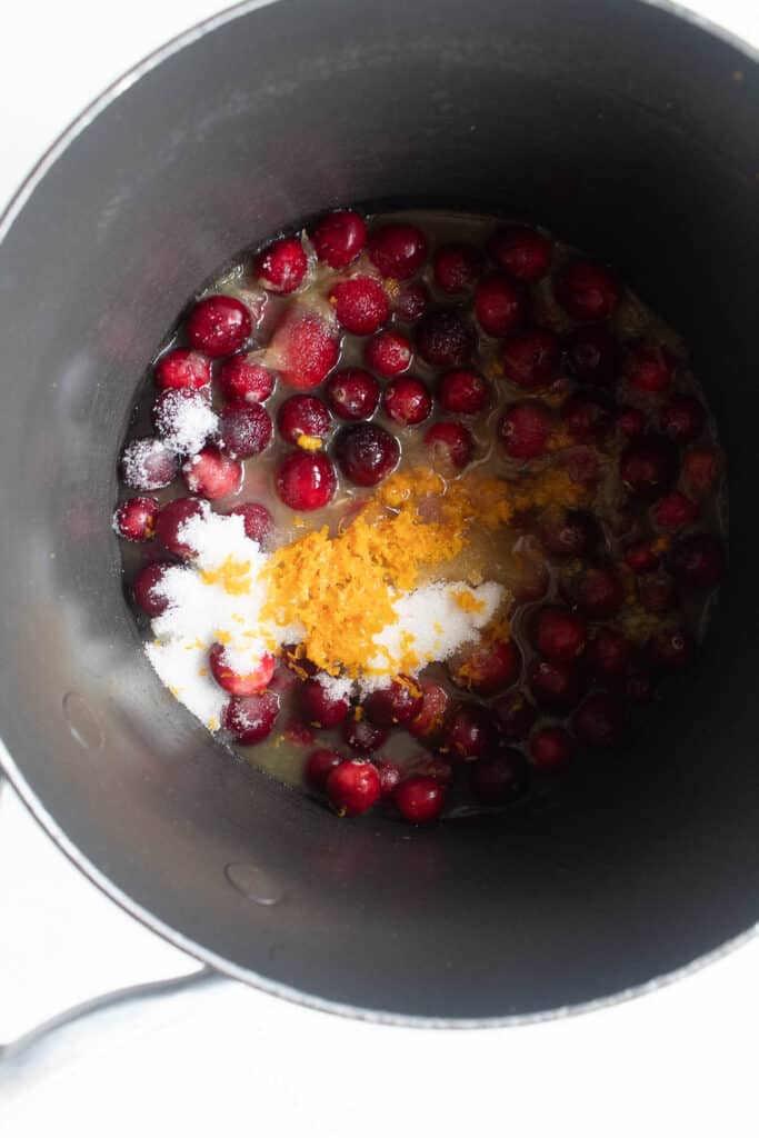 Fresh cranberries, orange zest, orange juice, and granulated sugar in a saucepan.