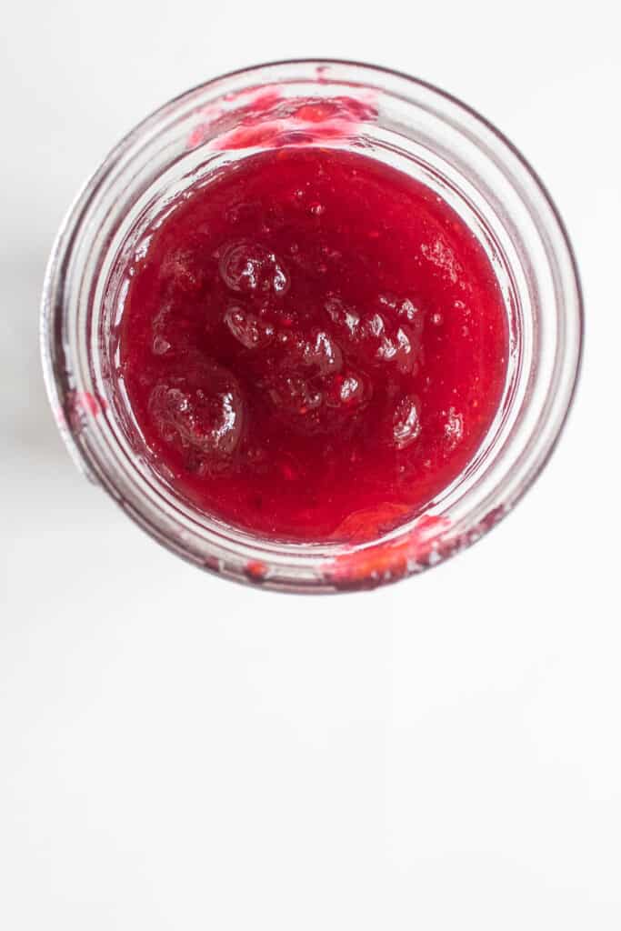 The bright pink homemade orange cranberry jam in a jar.