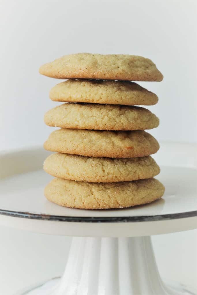 A tall stack of golden-edged cookies sitting on a white plate with a black rim.