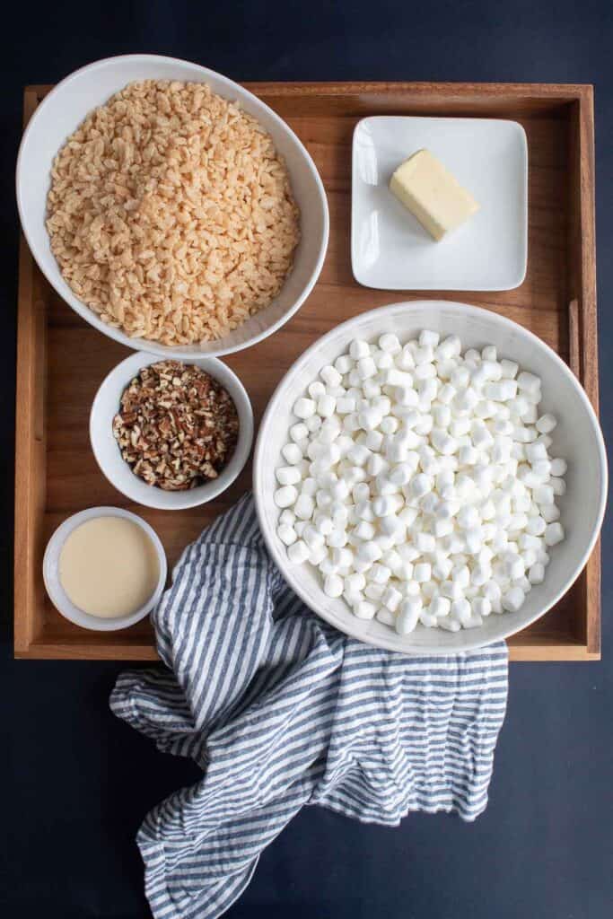 Ingredients for Soft and Chewy Buttered Pecan Rice Krispie Treats displayed in a square wooden platter.