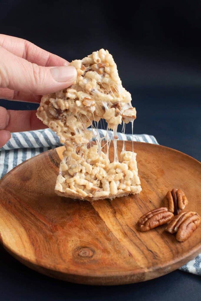 A soft rice krispie treat being torn into two pieces.