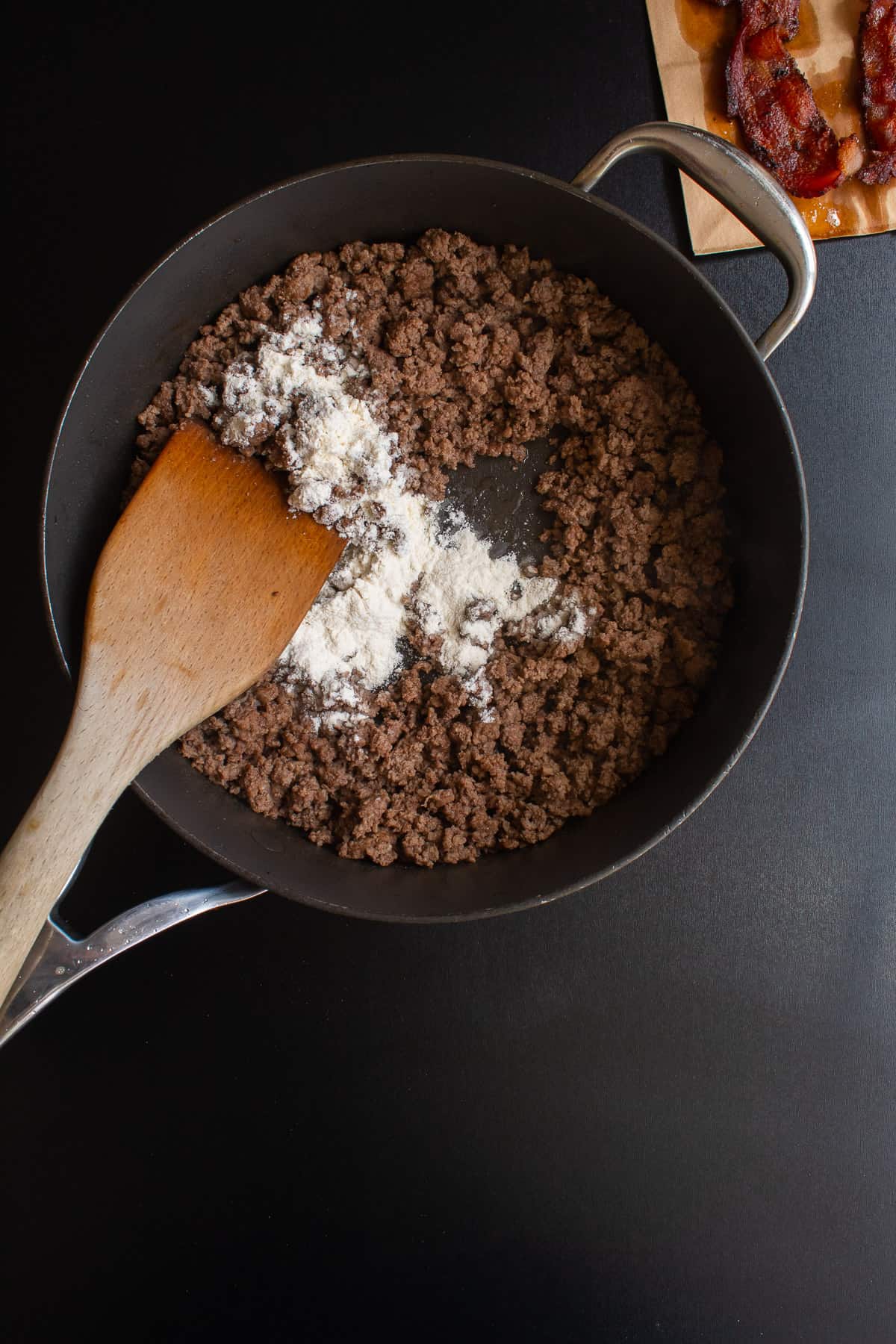 Flour added to the browned ground beef in a skillet.
