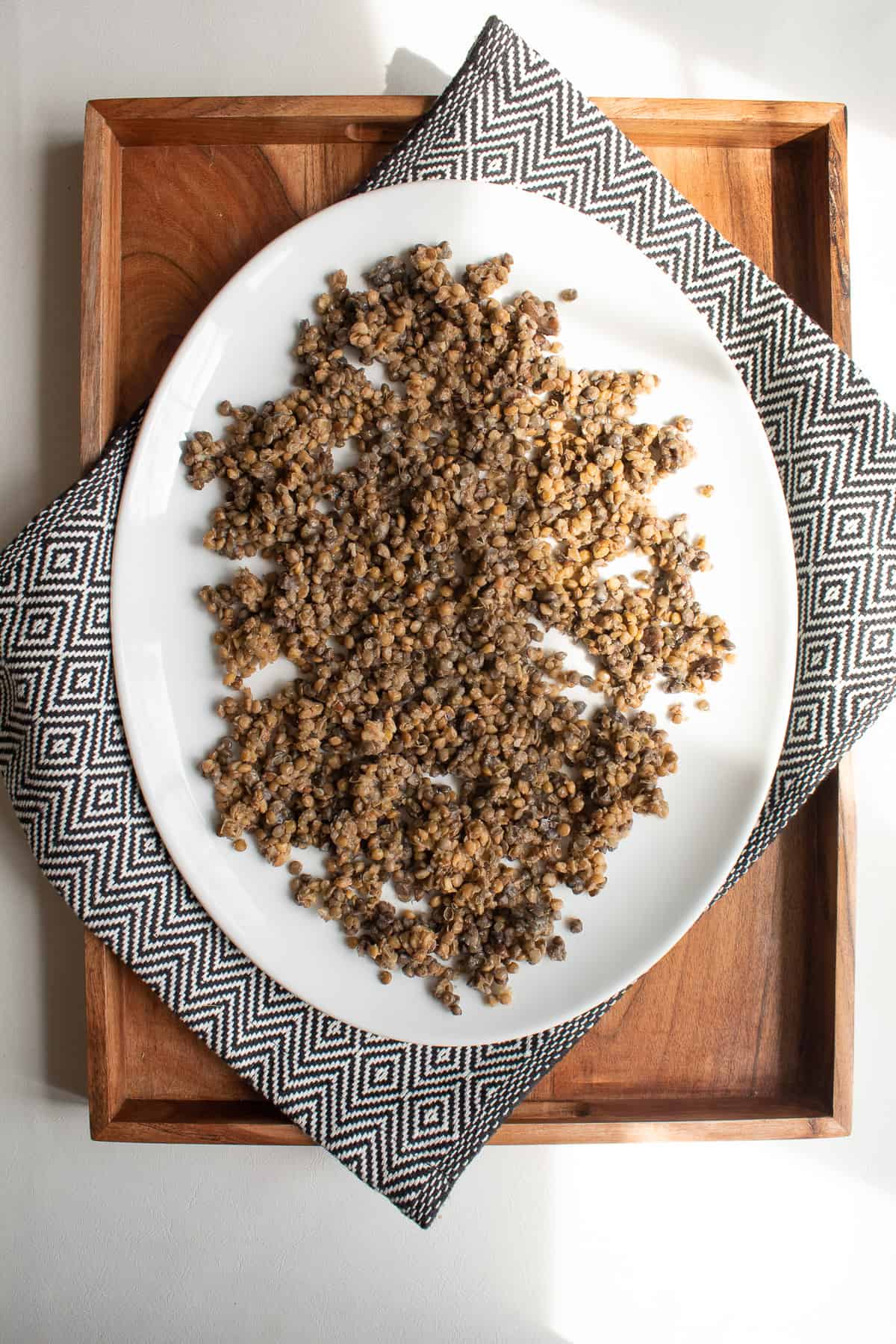 Cooked lentils layered on a a large white platter.