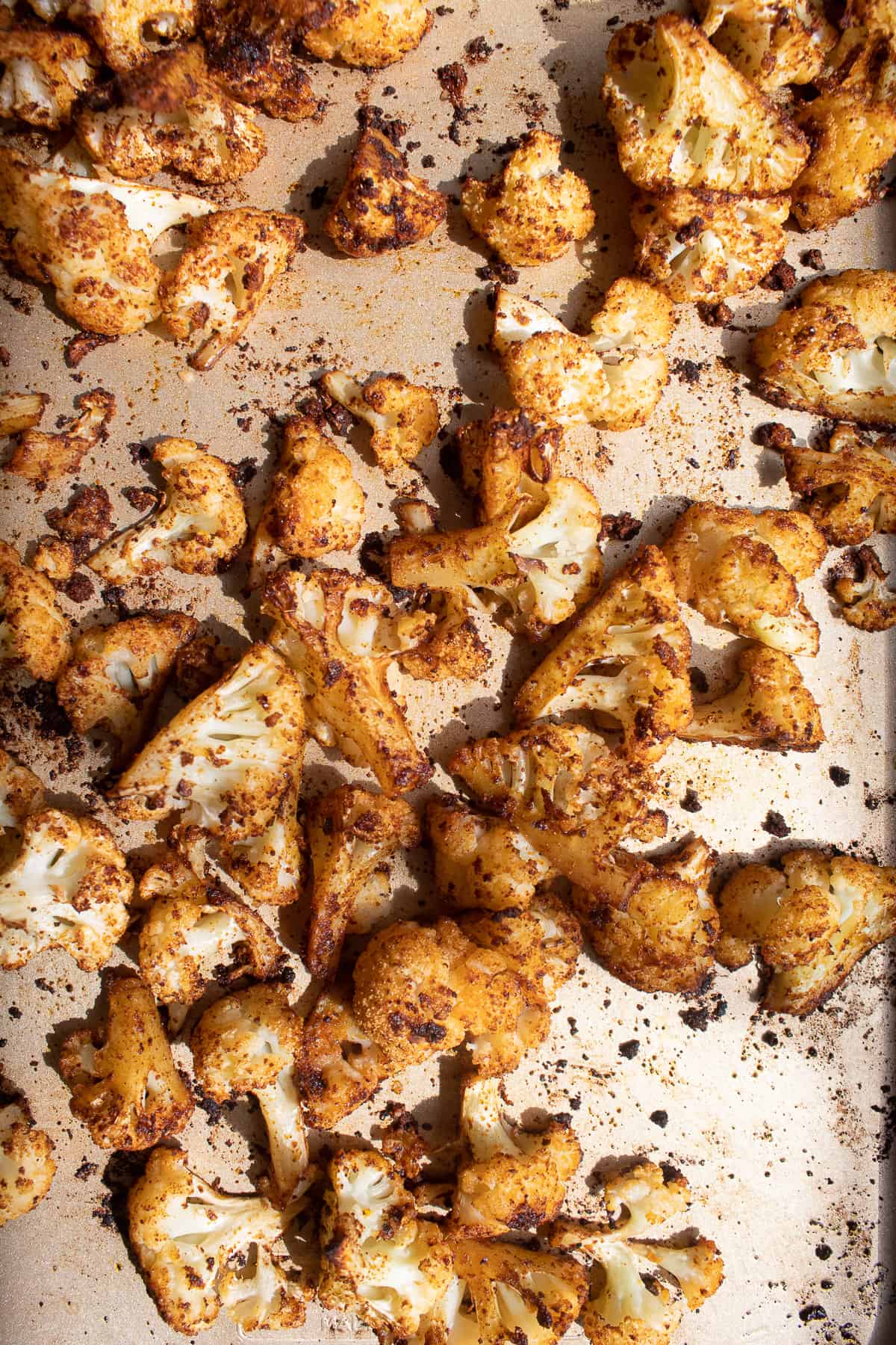 The roasted cauliflower with crispy browned bits on a sheet pan.