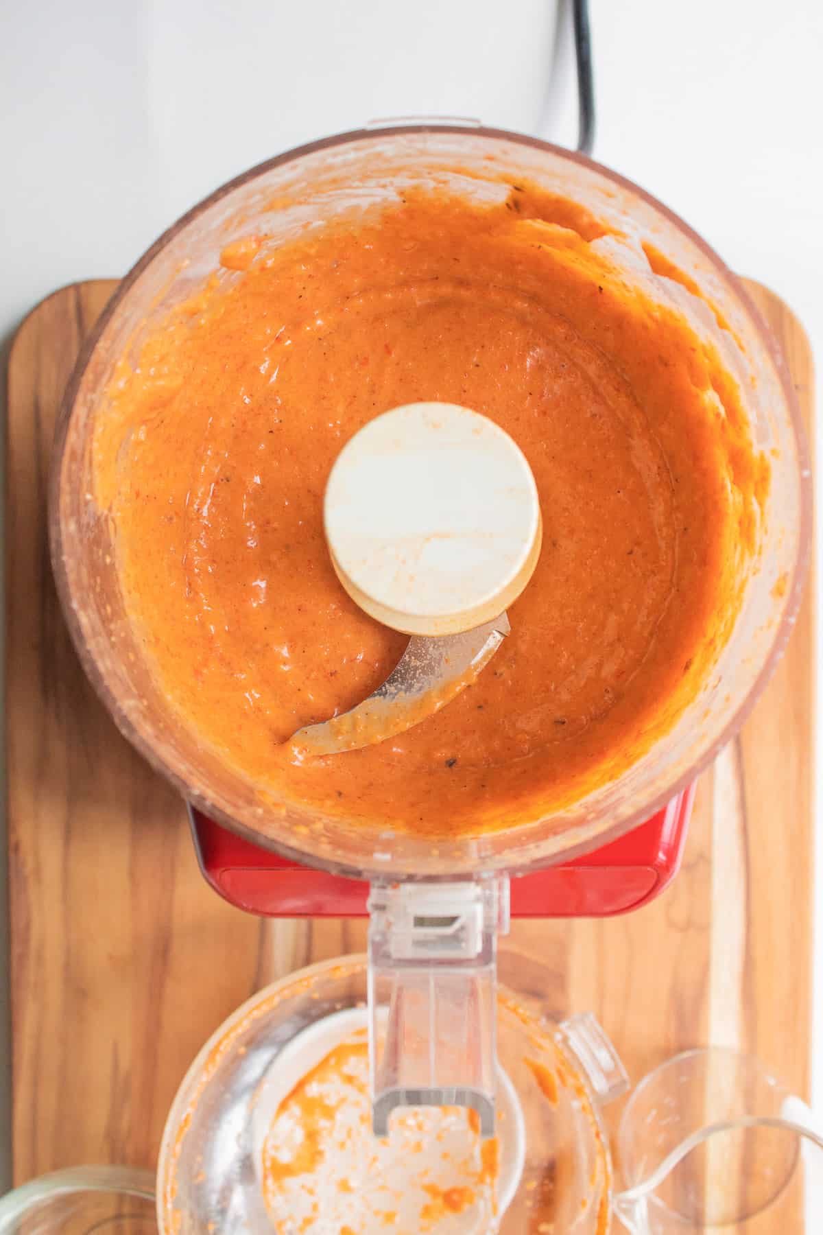 The bright orange-red processed salad dressing sits in the bottom of the food processor bowl.