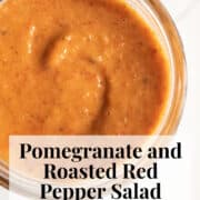 An reddish-orange dressing with specks of black pepper and roasted red pepper is swirled in a glass jar.