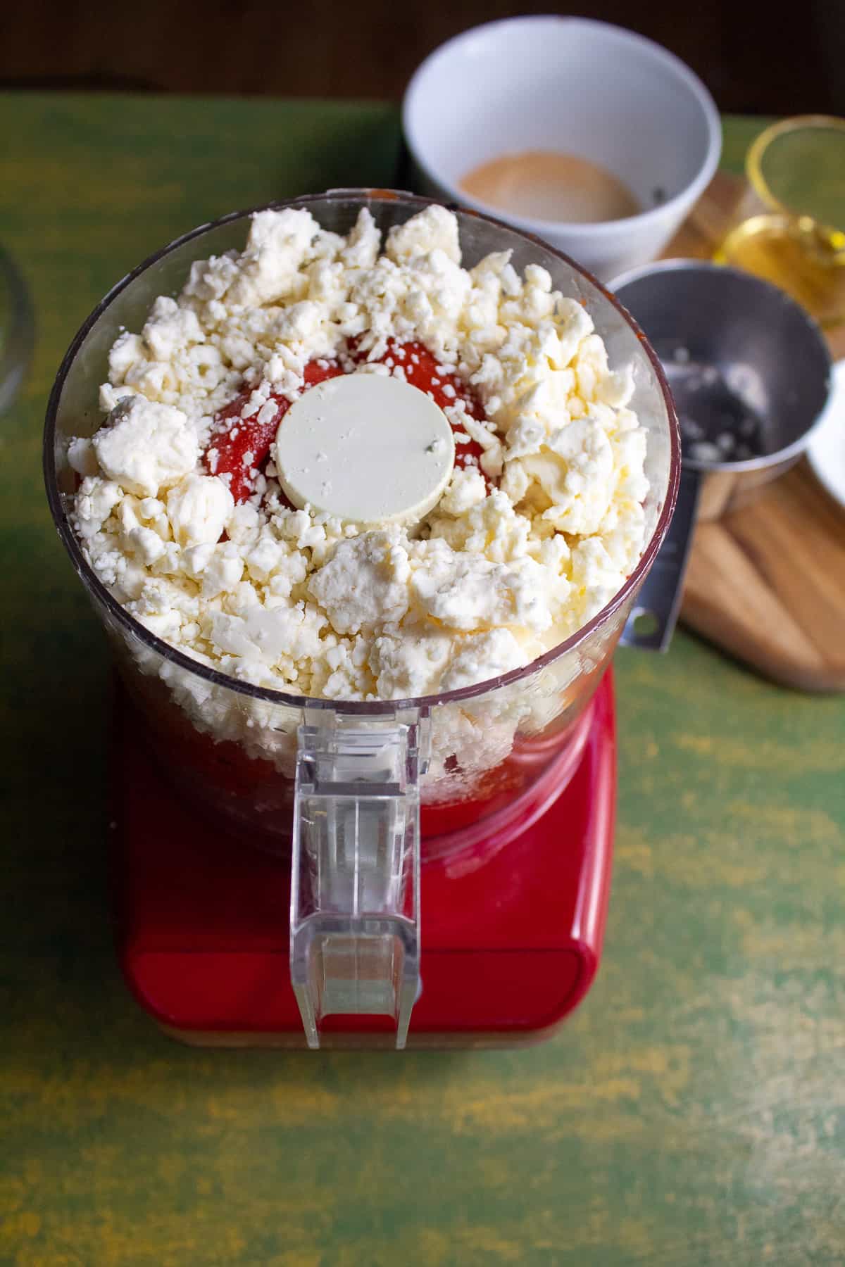 A mini food processor filled with the ingredients for the roasted red pepper sauce.