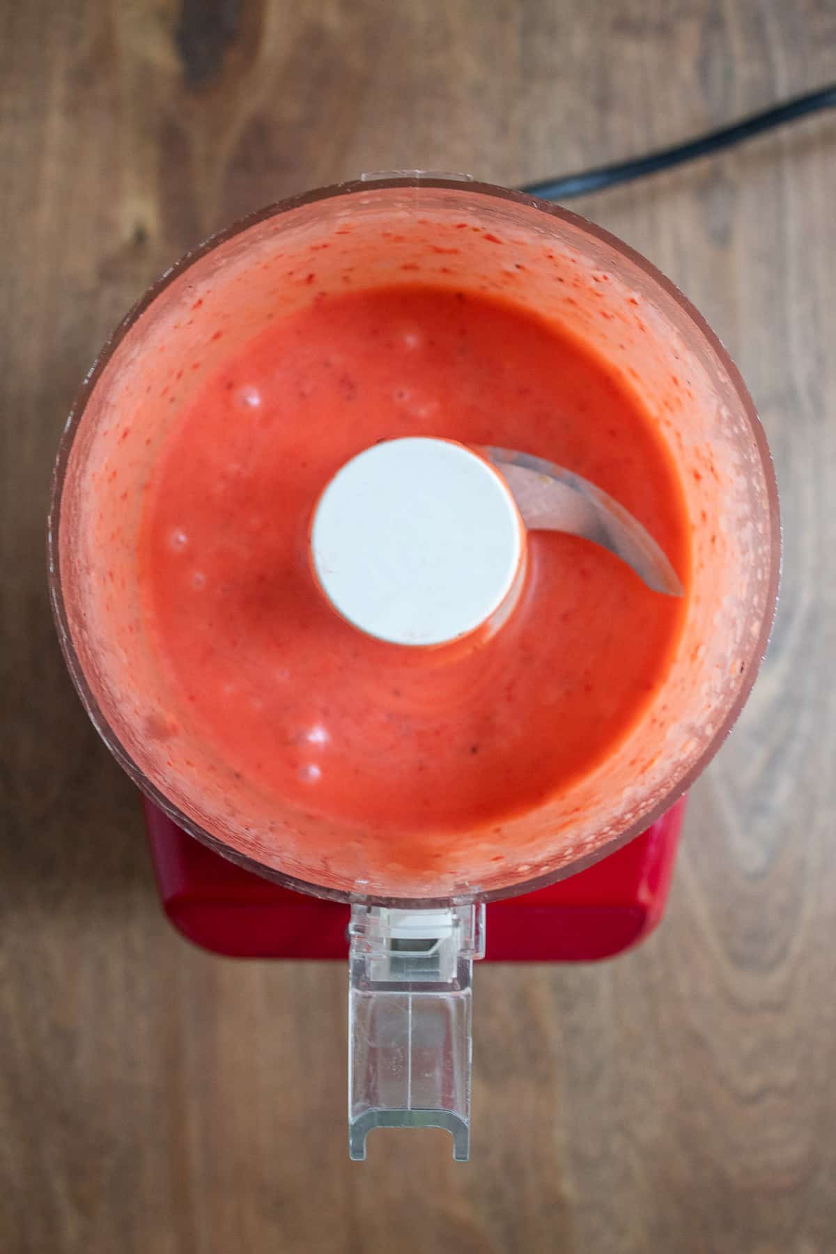 The bright pink mixed vinaigrette in the bottom of the food processor.