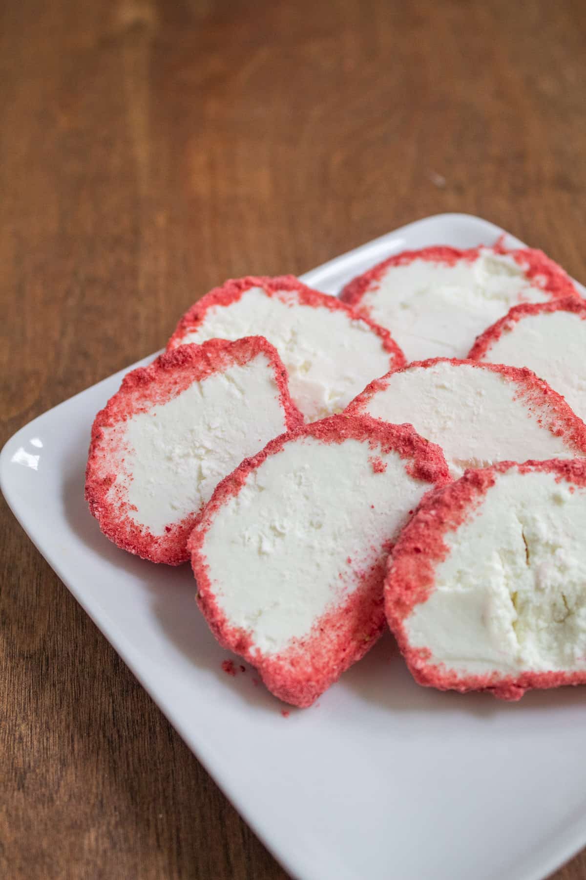 Goat cheese rounds are coated in a pink strawberry powder.