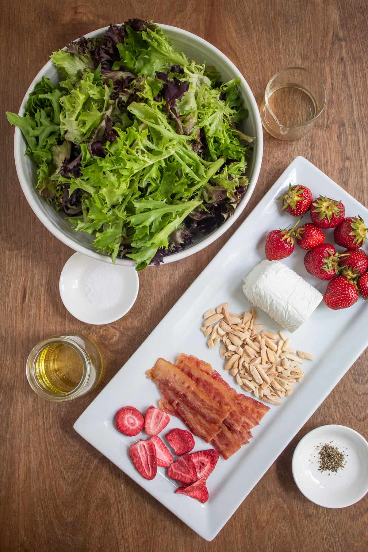 Ingredients for the salad are laid out on a brown wooden surface.