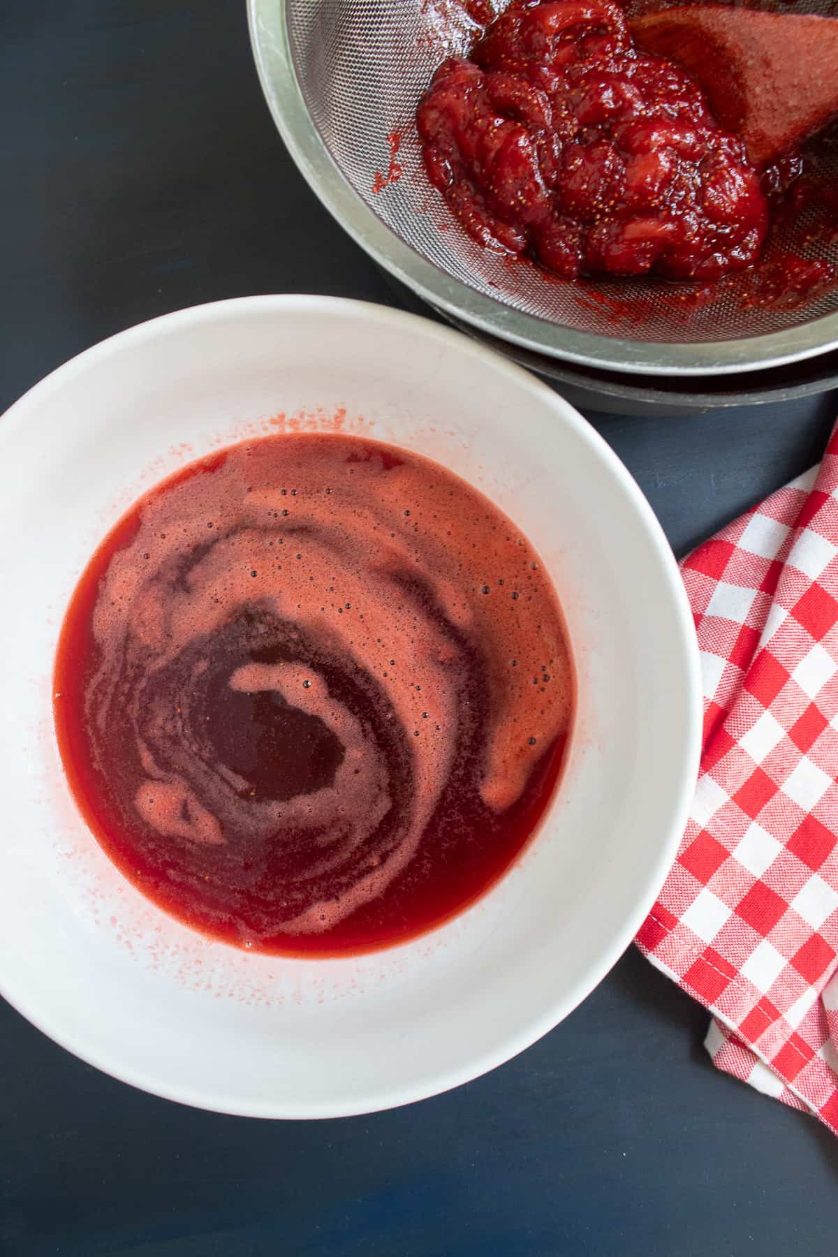 The strained simple syrup is in a large white bowl on a blue surface.