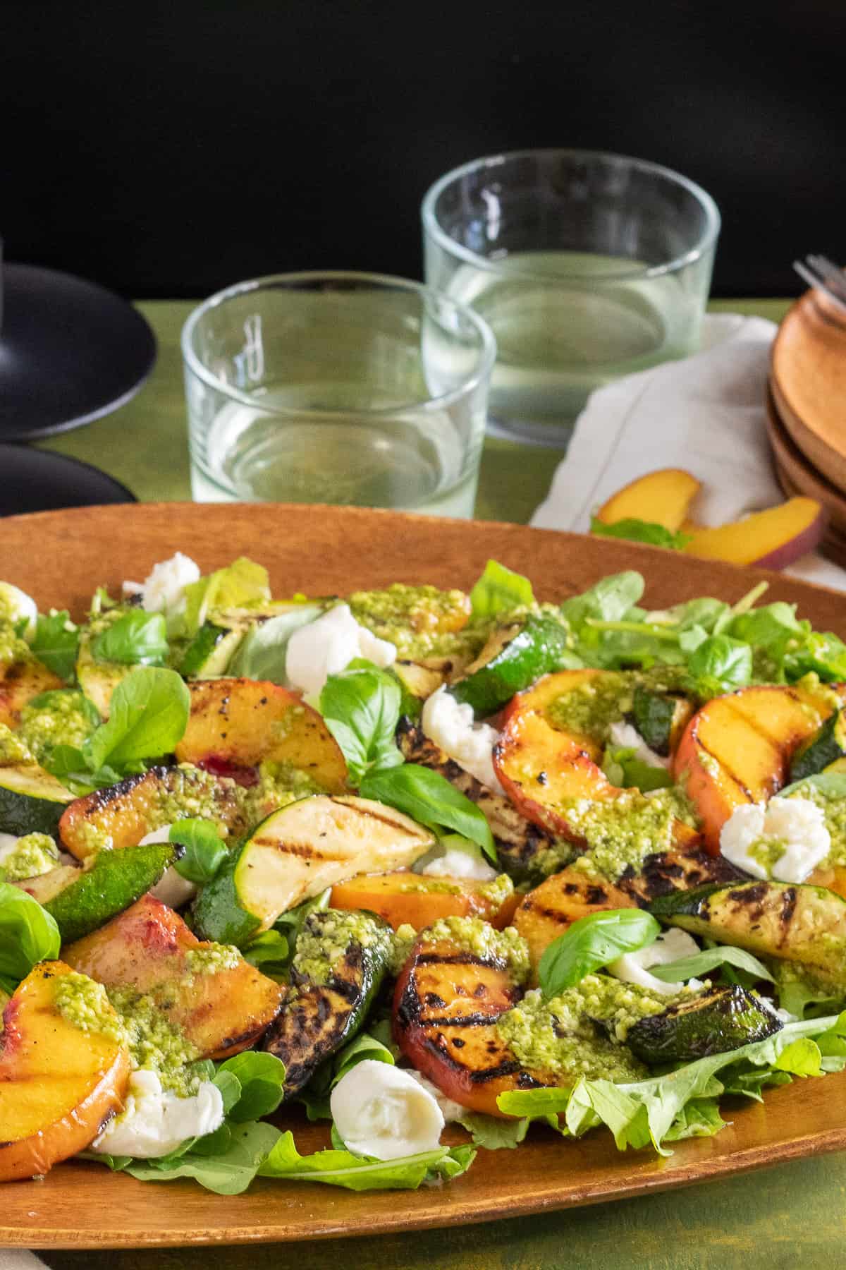 A close-up of a wooden platter displaying the salad on a green table.