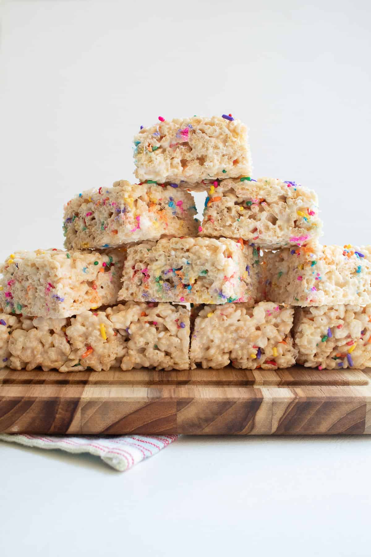 Finished treats are stacked 4 layers high on a wooden cutting board.